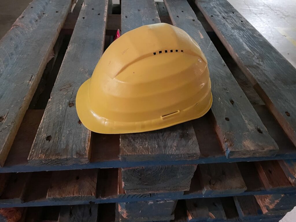Um Capacete Amarelo Repousa Sobre Um Pallet De Madeira cigfVTfU39I