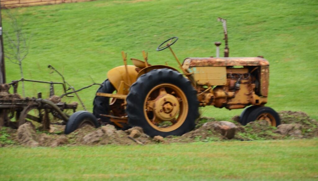 Um Velho Trator Amarelo Fica Em Um Campo Gramado ykFWsoQKGaM