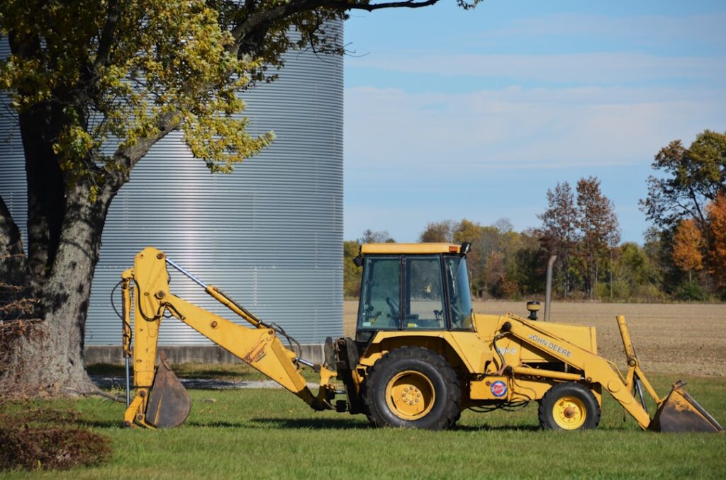 Retroescavadeira Amarela Estacionada Ao Lado De Um Grande Silo zU0htI8Y55M