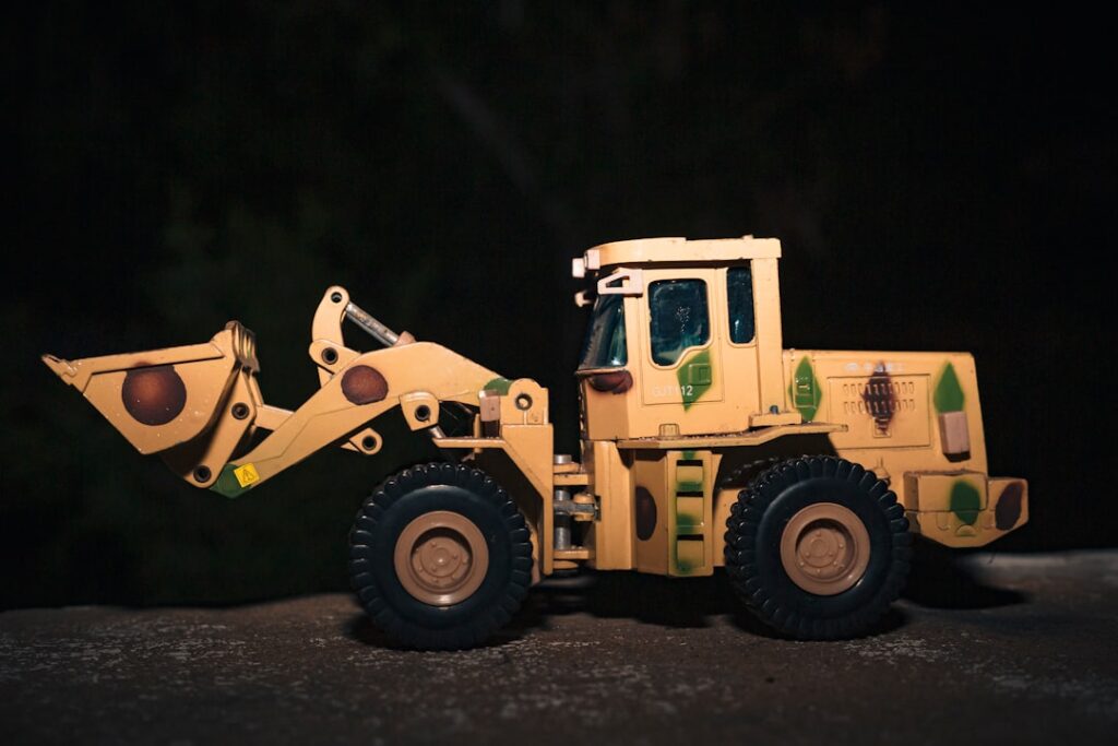 Um Caminhao De Brinquedo Amarelo Com Uma Pa Em Cima Dele whoONEl094E