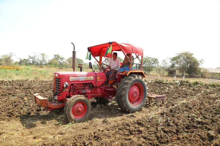 Um Homem Dirigindo Um Trator Vermelho Em Um Campo 3Iat1cAenCI