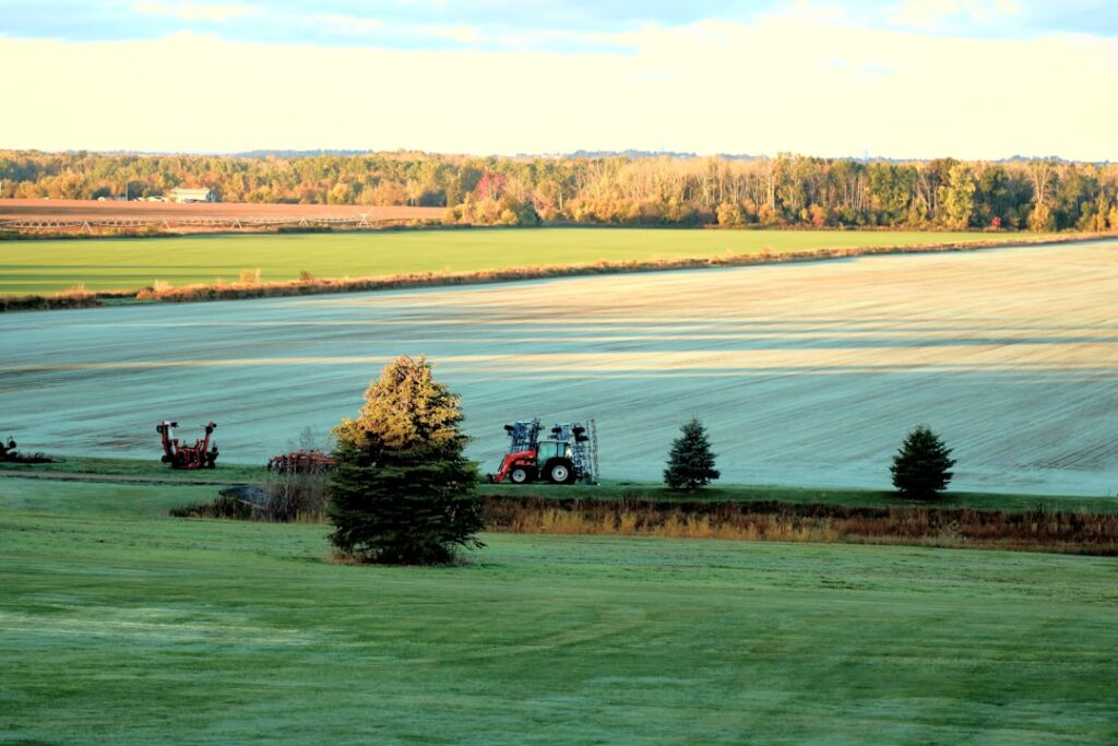 Trator Em Um Campo Com Arvores E Colheitas pHbYmzEiVAc
