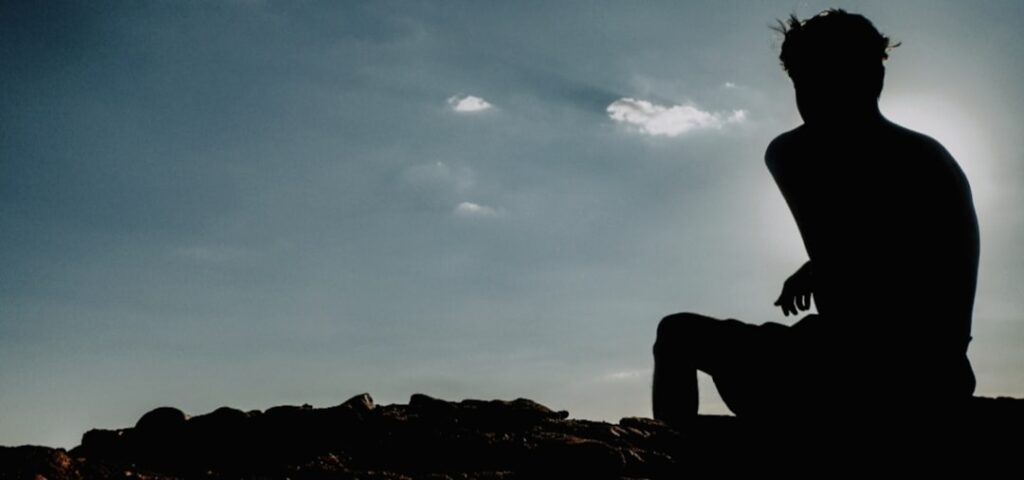 Uma Silhueta De Um Homem Sentado No Topo De Uma Montanha sVsFtaUtsKo
